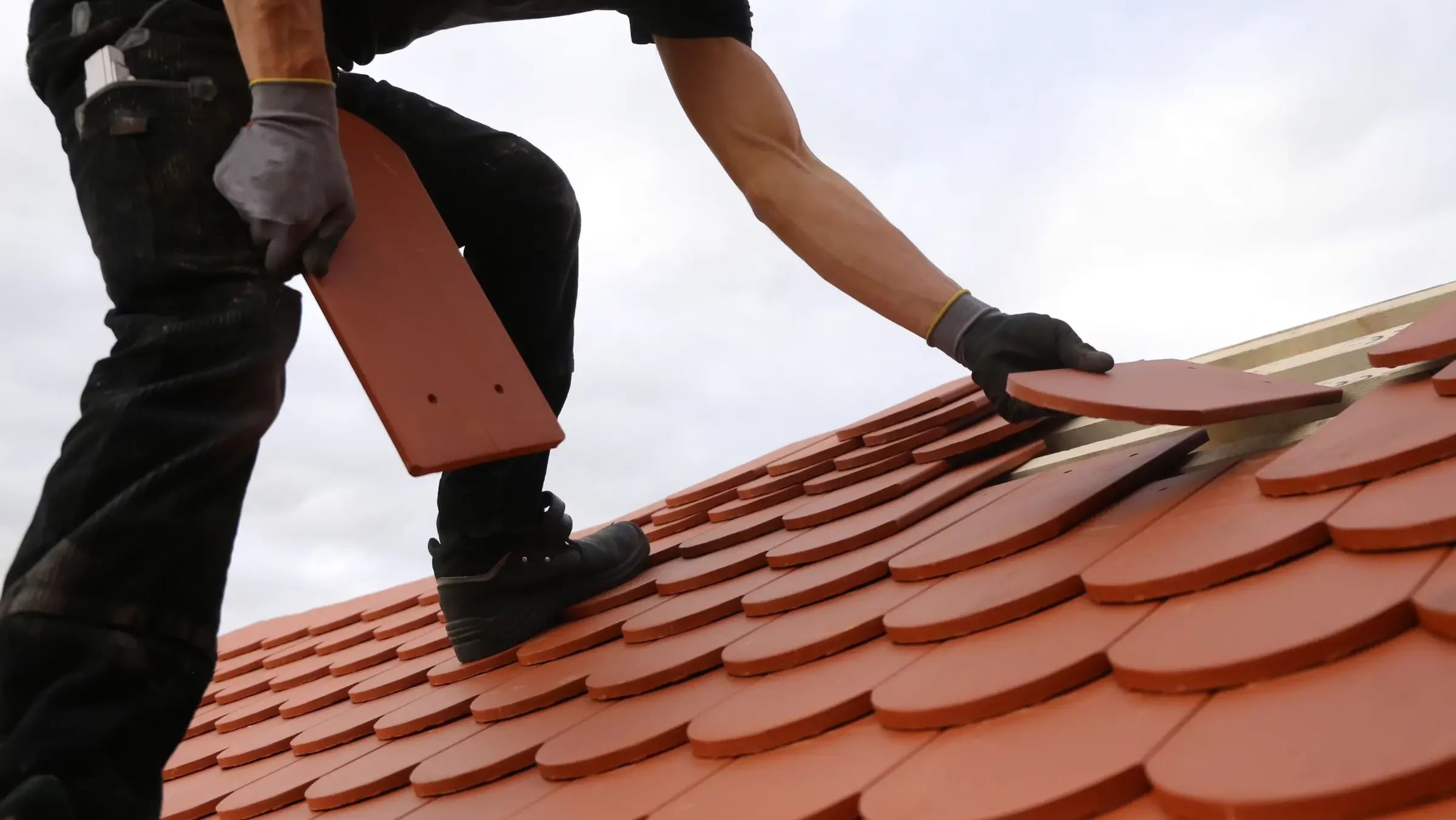Pose de tuiles par un artisan sur une toiture