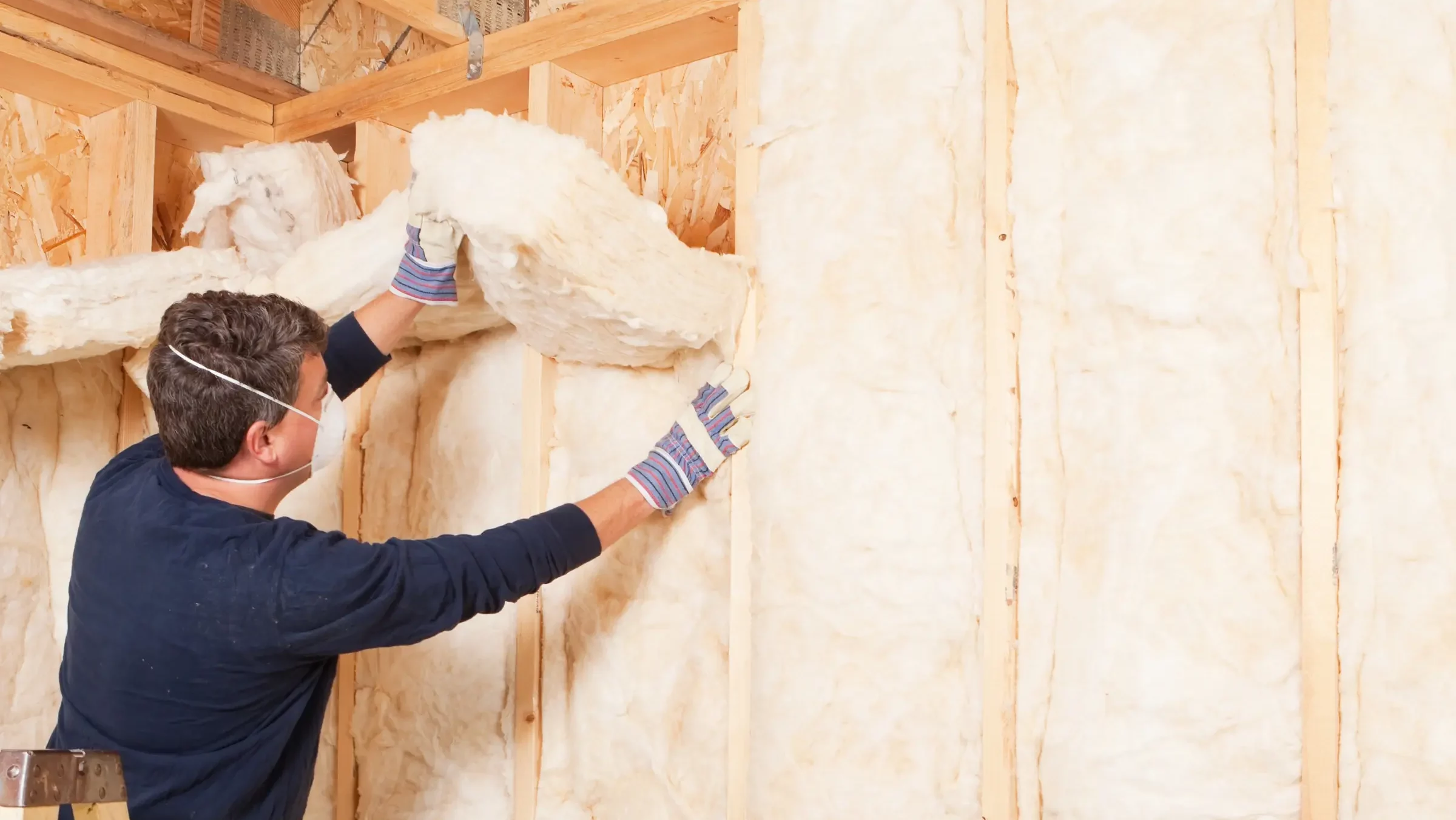 Pose d'isolant sur le mur d'une maison par un artisan